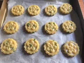 将圆球用月饼模具压扁，无月饼模具则用手掌压扁即可；（针对使用月饼模：首先建议选择简单的图样，太过复杂精细难脱模；然后使用前可以给花片撒上一层薄薄的面粉防粘，方便脱模；其次压模时一定要施力均匀、一步到位否则厚薄不一致，反复压还易造成多条压痕影响美观，如果不满意则重新揉圆重新压扁；最后压膜时压下弹簧手柄到底（压实）后放松弹起，再稍抬起月饼模离桌约几厘米距离悬空，再次往下轻压手柄将饼干片轻轻推出即可）