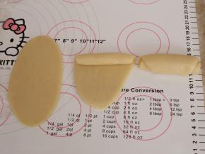 包好的水油皮收口朝上，用擀面杖从中间往上和往下擀开，由上往下卷起来，这样就完成了第一次擀卷。