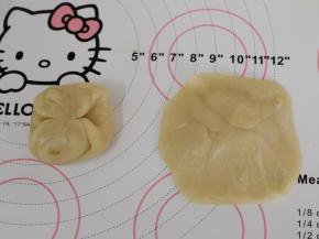 取一份松弛好的面团，从中间按压下去，将两头按到中间，用擀面杖擀成中间厚四周薄的圆形。