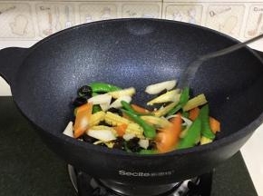 接着先倒入胡萝卜片翻炒变色，继续倒入黑木耳、山药、荷兰豆和玉米笋翻炒几分钟至熟。