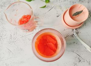 把大部分的西柚肉倒入榨汁机中，剩余少量西柚肉用工具捣碎，留于杯中。