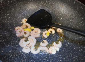 锅中虾油升温后，把姜片放入爆香，再把虾仁倒入炒制。