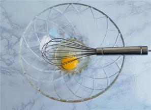 备一个无水无油的料理盆磕入鸡蛋，用打蛋器搅拌下。