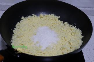 把打碎的绿豆泥倒入炒锅里，接着倒入白砂糖，炒至白砂糖软化溶解。接着放麦芽糖，炒均。