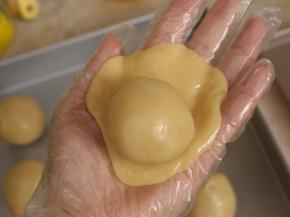 取一个饼皮，压扁，放上莲蓉馅。