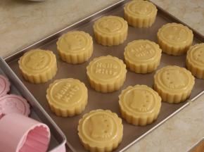 将月饼面团放入月饼模中，移到烤盘上，印出花纹。（压月饼时可以开始预热烤箱，上下火200℃）。