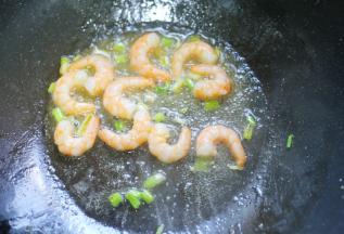 起锅烧油，放入葱白爆香，加入虾仁。