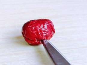 取一颗红枣，用剪刀从红枣的中间剪开，如图。