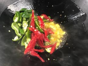 放入蒜末爆香，接着放入青、红辣椒炒香