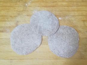 将小剂子压扁，擀成中间稍厚边缘薄的包子皮。