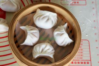 水晶虾饺是半月形，蝴蝶肚共有十二褶，这是粤式经典的水晶虾饺做法。做好的饺子，放入竹编蒸笼。