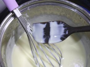 小火加热牛奶液，边加热边用手动打蛋器搅拌，一直熬煮到牛奶液变得浓稠，挂在刮刀上能划出清晰的纹路。