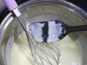 小火加热牛奶液，边加热边用手动打蛋器搅拌，一直熬煮到牛奶液变得浓稠，挂在刮刀上能划出清晰的纹路。
