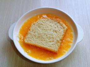 再把吐司片放入蛋液中，将两面均匀裹上蛋液。