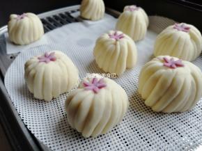 把小花放在顶端，为了使小花粘得更牢固，用手指沾一点点水在其中一面，再放上去。放在温暖处醒发20-30分钟，看见馒头胚明显大了一些，才可以上锅蒸