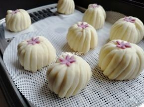 把小花放在顶端，为了使小花粘得更牢固，用手指沾一点点水在其中一面，再放上去。放在温暖处醒发20-30分钟，看见馒头胚明显大了一些，才可以上锅蒸