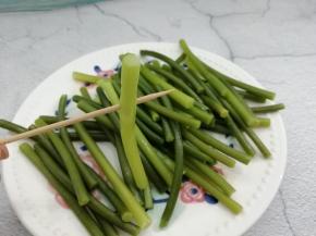 用牙签从蒜苔的中间划开，划成四条