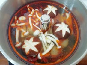 锅开以后，先下入不容易熟的食材，比如火锅丸子、香菇、白玉菇和豆腐皮，盖上锅盖中火煮5分钟左右。