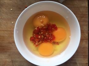 碗中磕入3枚鸡蛋，2勺剁辣椒；（加入剁辣椒用于提味，如果没有则加入适量盐调味，料酒去腥）