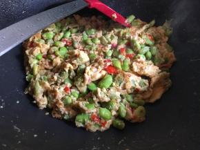 中小火定型后再进行翻炒，鸡蛋炒熟、加入少许糖调味翻拌均匀后出锅即可；（一定要注意是中小火，避免火力太大鸡蛋煎糊；其次鸡蛋液最好凝固以后在翻炒，这样鸡蛋可以均匀地沾在毛豆上了，同时如果不想要太碎则尽量减少翻炒频率。如果喜欢鸡蛋嫩一点则可以少炒一会，利用余温炒熟；）