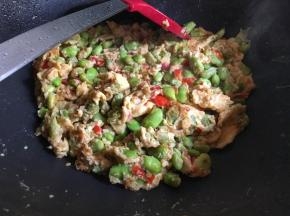 中小火定型后再进行翻炒，鸡蛋炒熟、加入少许糖调味翻拌均匀后出锅即可；（一定要注意是中小火，避免火力太大鸡蛋煎糊；其次鸡蛋液最好凝固以后在翻炒，这样鸡蛋可以均匀地沾在毛豆上了，同时如果不想要太碎则尽量减少翻炒频率。如果喜欢鸡蛋嫩一点则可以少炒一会，利用余温炒熟；）