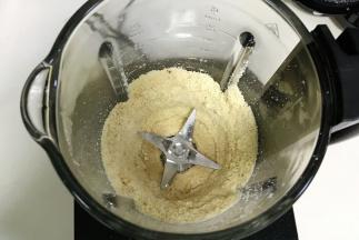 启动破壁机搅打程序，中途可以用刮板刮下粘在壁上的花生粉末，直至打到稍微细腻时，加入花生油。