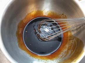 把黑糖糖浆直接倒入打蛋盆内称量好，加入枧水，用蛋抽轻轻搅打均匀，接着再加入花生油，再次搅匀。