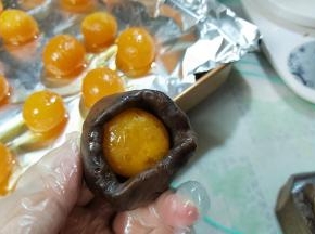 把豆沙馅搓成一个球，压扁，边缘捏薄一点点，包住蛋黄，豆沙贴近蛋黄收拢成一个圆球。