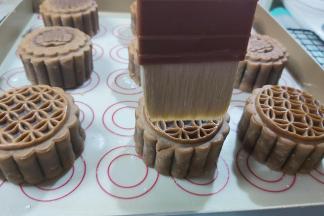 把蛋黄加上牛奶、盐，搅匀，然后取出月饼，放置手温，用毛刷沾上一点点蛋液，用毛尖的五分之一处，轻轻并且快速的在月饼表面刷两下。