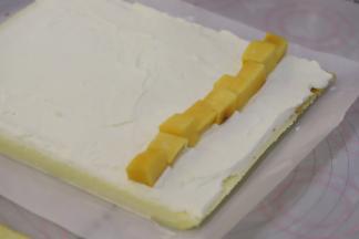 蛋糕卷正面抹好奶油，摆放上黄桃块。