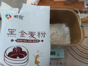 把中筋面粉、黑米面粉、水、酵母、奶粉一起放入面包机的桶内，启动MIX程序，和面20分钟。（没有MIX程序的面包机，直接选择和面的选项即可）