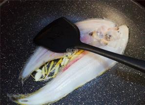 首先热锅倒入冷油，升温后把蒜片，姜丝放入爆香，舌鳎鱼去皮洗净后放入锅中煎制。