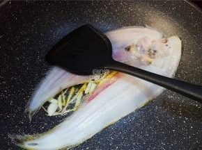 首先热锅倒入冷油，升温后把蒜片，姜丝放入爆香，舌鳎鱼去皮洗净后放入锅中煎制。