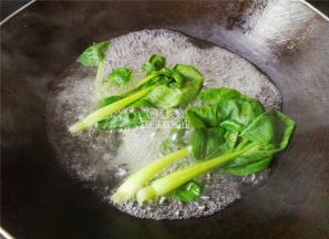 首先煮一锅沸水，把青菜洗净水沸腾了放入烫熟，捞起备用。