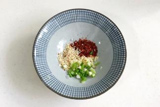 面碗中加入1勺白芝麻、1勺葱花、1勺蒜蓉和1勺辣椒面。