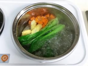 把油菜、玉米笋和胡萝卜片下沸腾的锅中焯熟，玉米笋可以多煮一会，然后捞出铺在面条上。