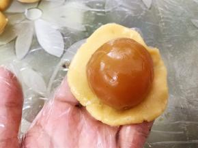 取一份饼皮压扁，放入一个莲蓉蛋黄