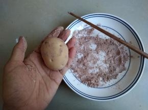 将包子放在可可粉和粘米粉（或者奶粉）的混合粉中，多余的粉拍掉，用筷子戳一个个小孔