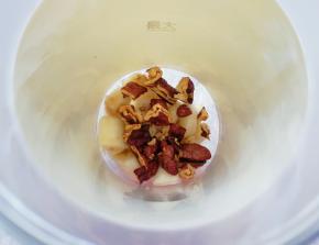 将香蕉块放入榨汁杯里，取一半的碧根果仁掰碎一同加入榨汁杯。