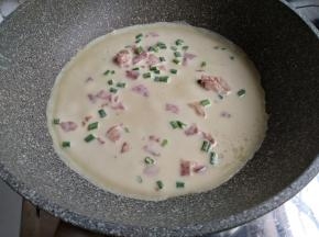 不粘平底锅里刷一层油，油不能太多，否则面糊很快成型，摊不圆。开小火加热不粘锅，不要用大火哟。然后将面糊勺进锅里，转动一下锅，使鸡蛋饼摊成圆形。这个分量可以做4块面饼