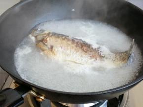 把一面煎黄后，再翻面煎另一面，煎鱼的时候少翻动，不要把鱼身煎碎。煎好后倒入没过鱼身的热水，倒入料酒，盖上锅盖