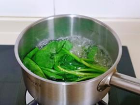 菠菜去根，冷水冲洗，再焯水，水开后加入几滴食用油，再放入菠菜，大火再次烧开立即关火，捞出过冷水。