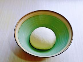 将揉均匀的面团取出，揉光滑，放入大口器具中，盖上保鲜膜进行发酵至原来的2倍大，可以用手指摁一下，不反弹，不回缩即为发酵完成。