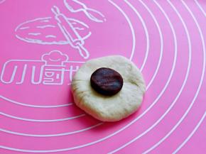 取一块面团，用掌心按压一下，不要压太薄，放上豆沙馅，如包包子的手法包起来，收口捏紧。