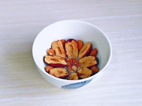 红枣一剪二，去掉枣核，依次摆放在小碗的边缘，碧根果放在中间，果仁摆放枣与枣的中间，如图。