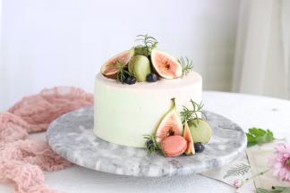 随意的将绿色奶油的红色奶油抹在蛋糕表面，利用抹刀抹平，表面放上无花果，马卡龙，蓝莓和迷迭香装饰。