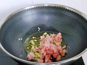 起油锅，加入蒜末炒香，再加入肉丁煸炒，炒制变色发白，加入料酒。