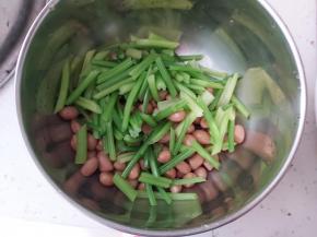 取一个干净的小盆，放入煮好的花生、芹菜，花生米跟芹菜都要沥水哟。
