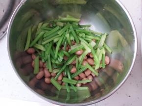 取一个干净的小盆，放入煮好的花生、芹菜，花生米跟芹菜都要沥水哟。