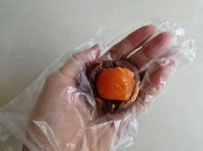 （咸蛋黄提前一天用玉米油泡着，做的时候再用烤箱150度烘烤7分钟，不要烤得太熟。）豆沙馅用拇指压个窝，把咸蛋黄放入。咸蛋黄和肉松豆沙加起来的重量是43克